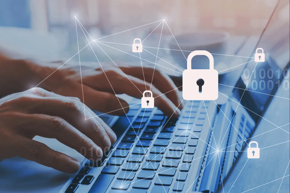 Hands typing on a laptop keyboard with digital lock icons representing cybersecurity and data protection.